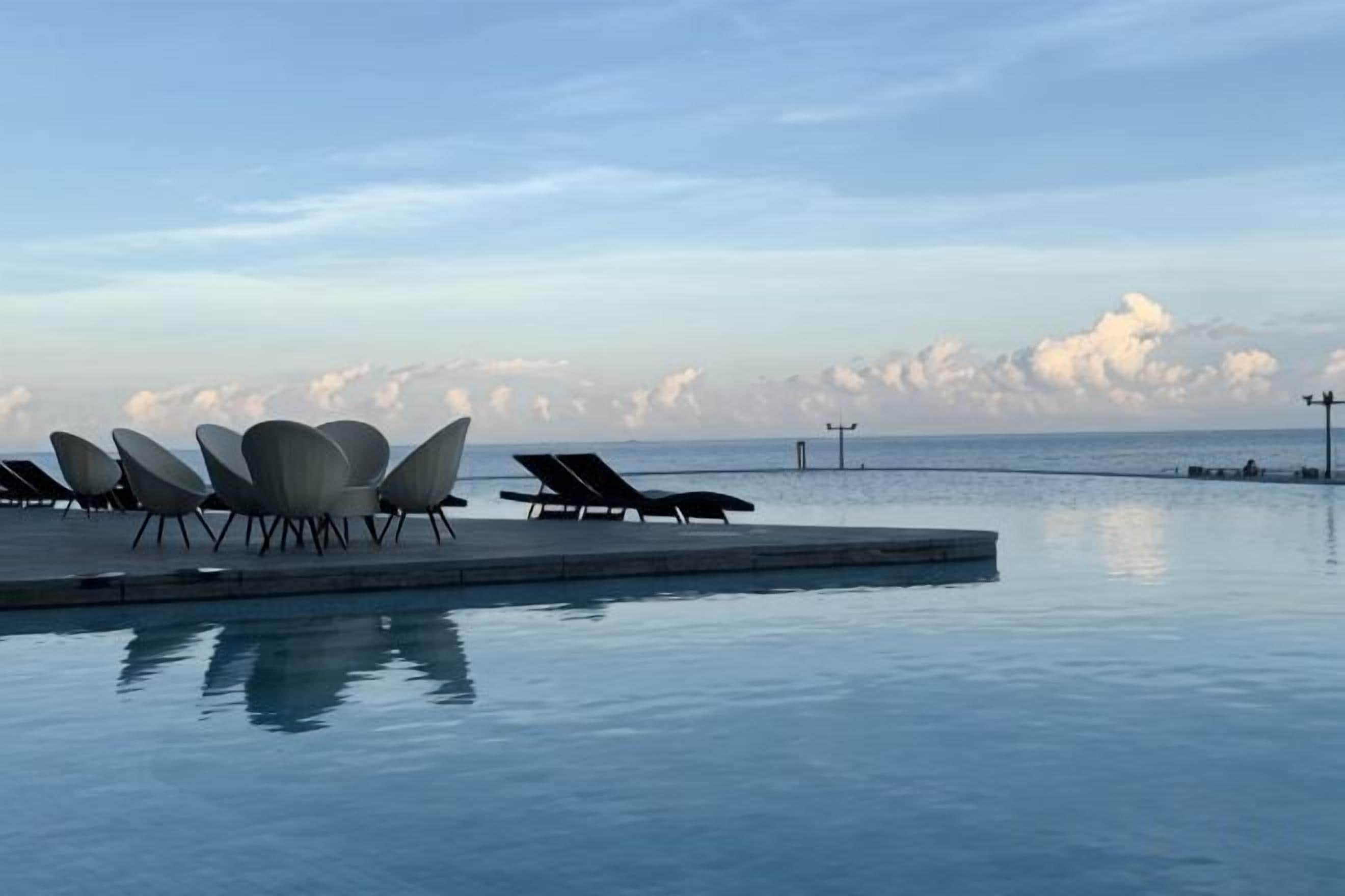 A poolside area with lounge chairs and a view of the sea.
