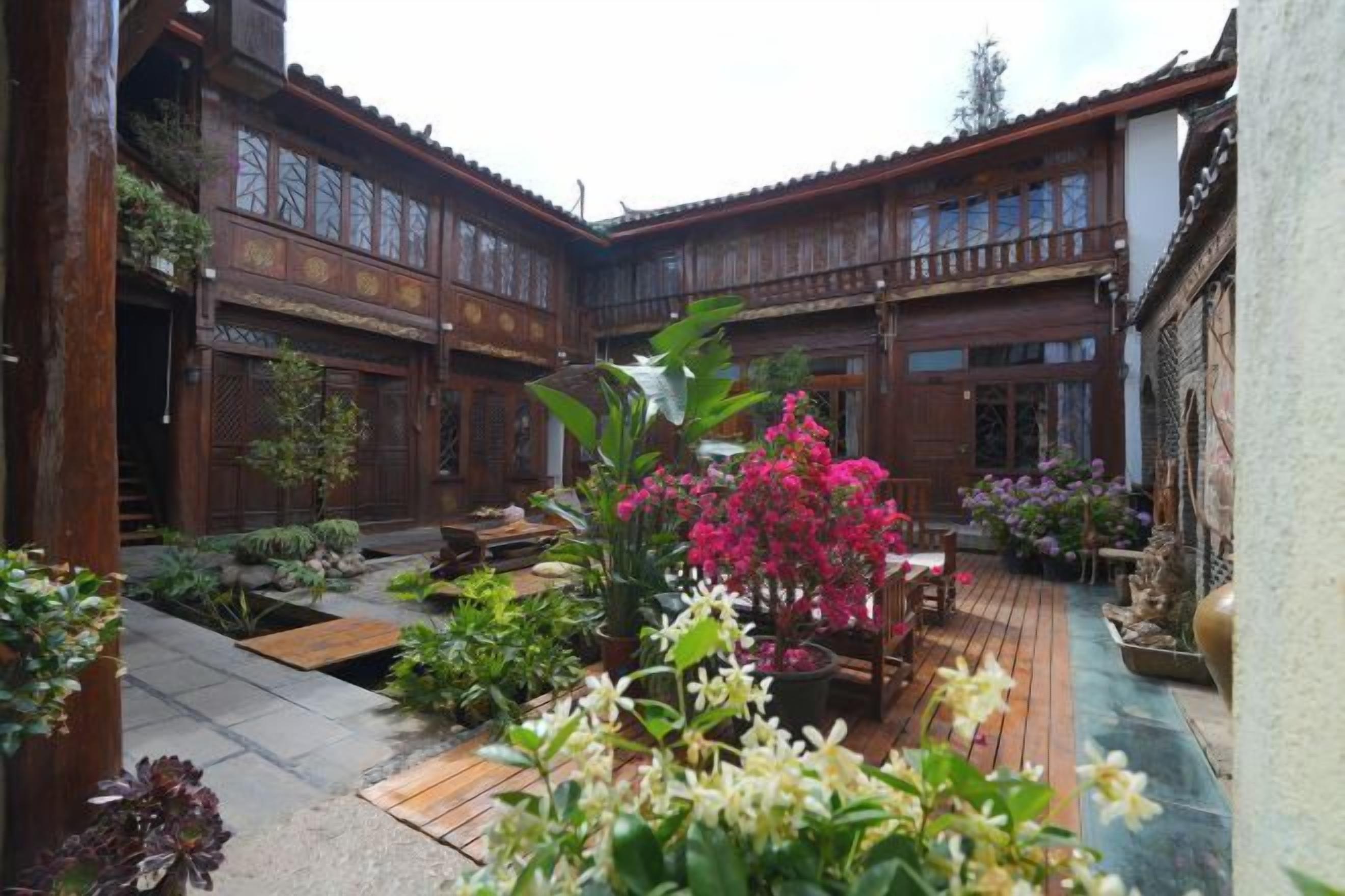 Un patio con arquitectura de madera, plantas en macetas y un pequeño espacio de estar.