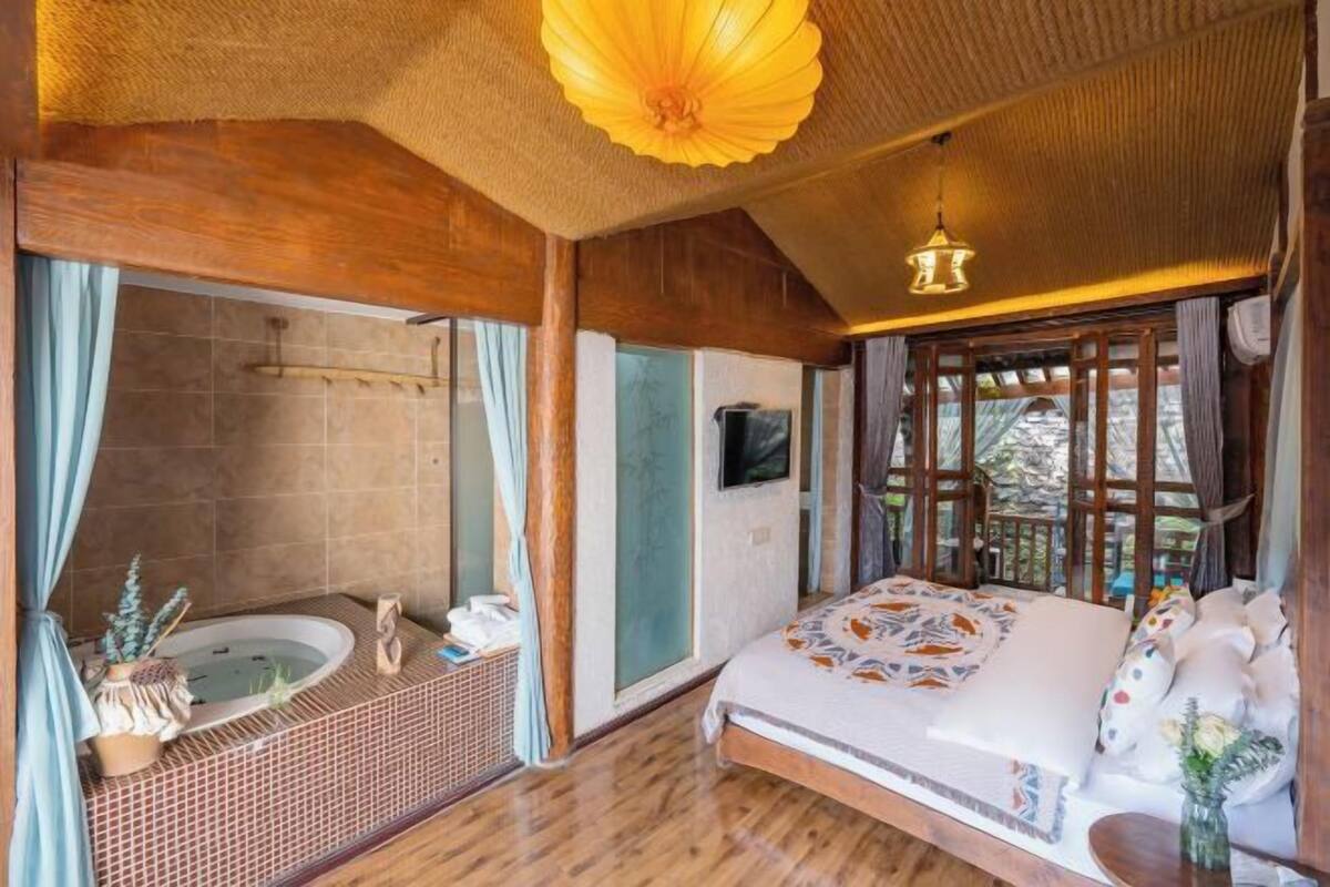 A room with a bed, a bathtub, and a large window.
