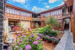 Un patio con arquitectura de madera, plantas en macetas y mobiliario exterior.