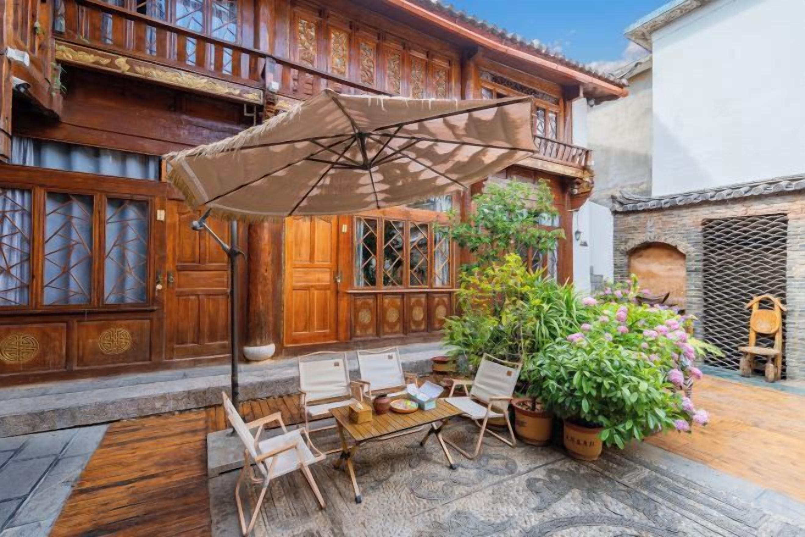 A traditional wooden building with a balcony, a dining area with chairs and a table, and a potted plant.