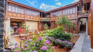 A courtyard with wooden architecture, a wooden deck, and potted plants.