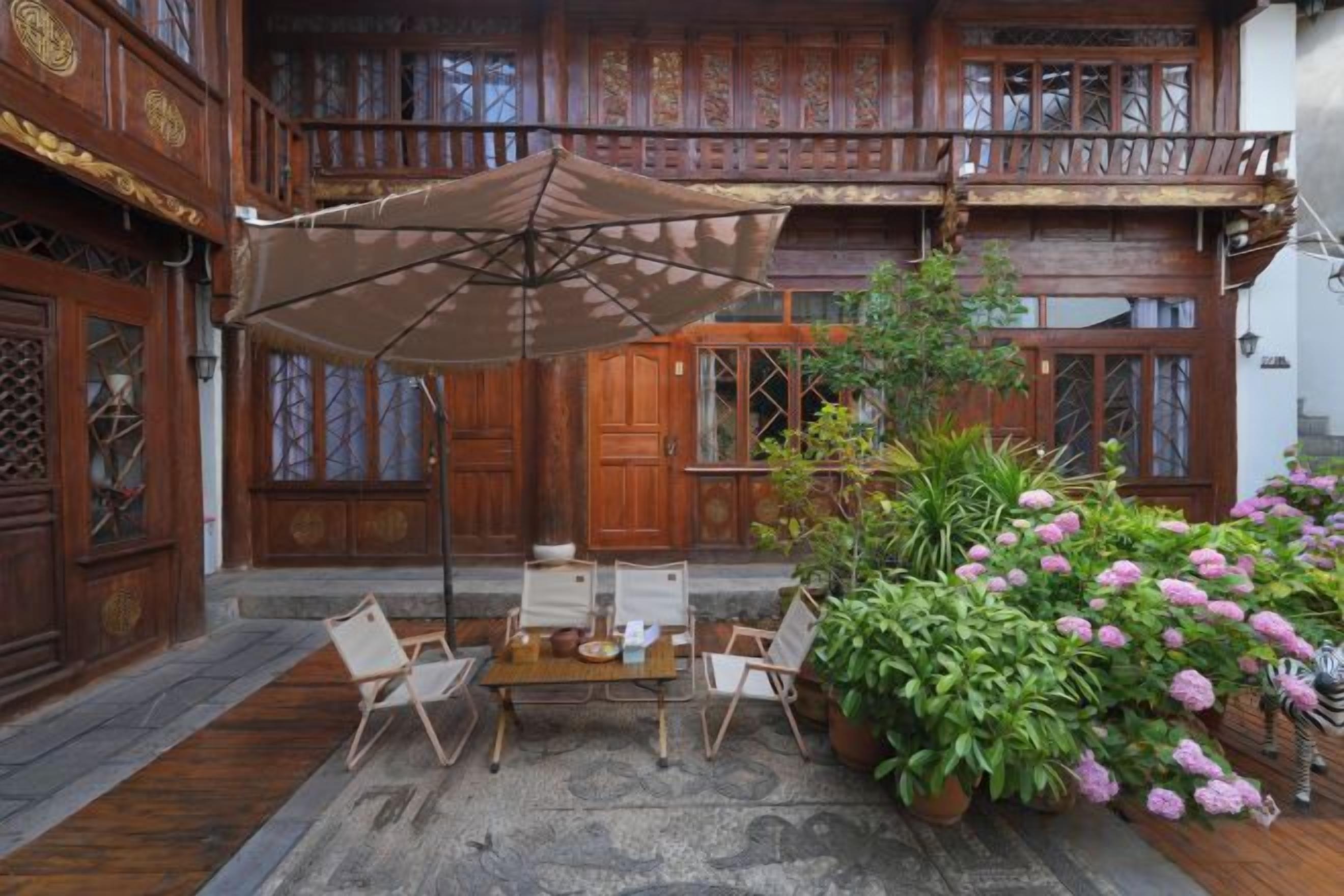 Ein traditionelles Holzgebäude mit einem Balkon, einem Tisch mit Stühlen und Blumentöpfen.