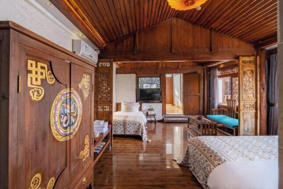 A traditional wooden room with a bed, a wooden cabinet with decorative carvings, and a television.