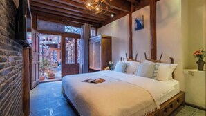 A bedroom with a bed, wooden beams, a TV, and a view of the outside.