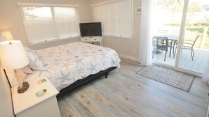 Ein Schlafzimmer mit einem Bett, einem Fernseher, einem Nachttisch und einer Schiebetür zu einer Terrasse.