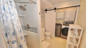 Ein kleines Badezimmer mit Dusche, Toilette und Waschmaschine.