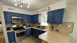 A kitchen with blue cabinets, a microwave, a stove, and a sink. - Bayside Retreat: Your Perfect Beach Getaway (Lower Township)
