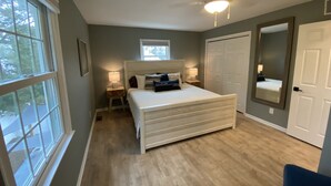 A bedroom with a bed, a ceiling fan, a window, and a door. - Bayside Retreat: Your Perfect Beach Getaway (Lower Township)