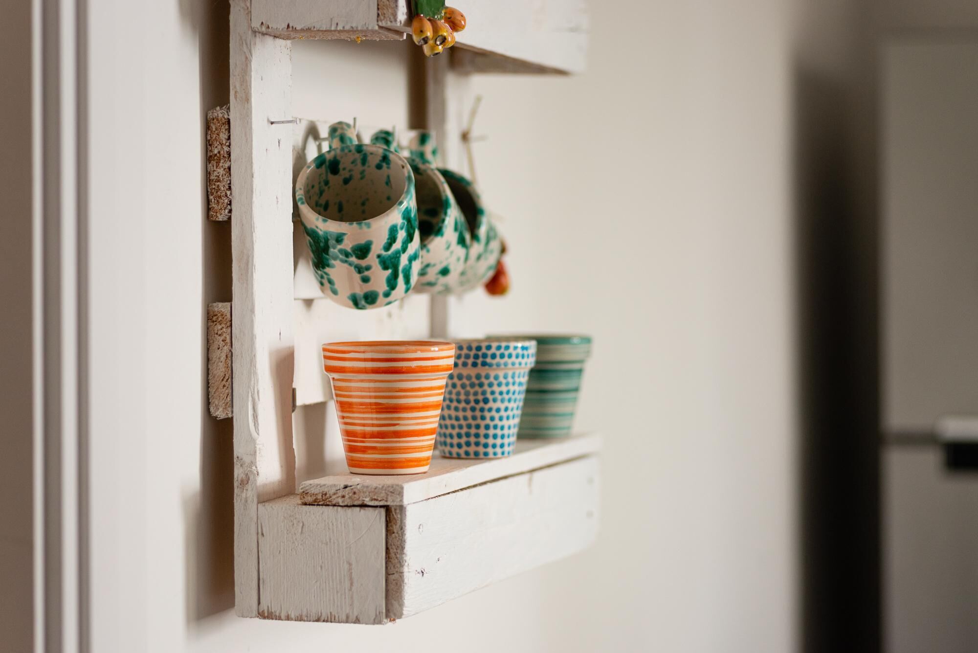 Une étagère rustique avec des tasses et des mugs en céramique.