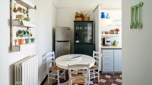 A kitchen with a refrigerator, a cabinet with glass doors, a dining table with chairs, and a radiator. - Le Cementine in Lecce (Lecce)