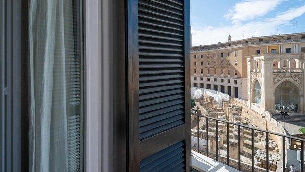 A balcony with a view of ancient ruins and a building with classical architecture. - Le Cementine in Lecce (Lecce)