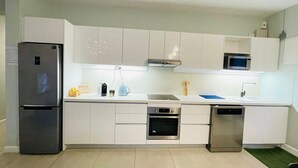 A modern kitchen with white cabinets, a stainless steel refrigerator, an oven, a dishwasher, and a microwave. - Beautiful Luxury 2-bed Apartment in Pereybere (Grand-Baie)