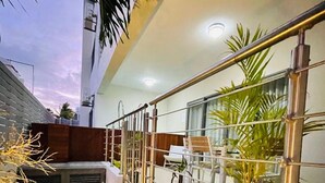 A modern outdoor balcony with a wooden bench, metal railing, and potted plants. - Beautiful Luxury 2-bed Apartment in Pereybere (Grand-Baie)