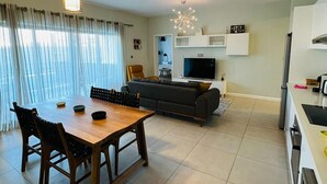 A modern living room with a dining table, sofa, and TV. - Beautiful Luxury 2-bed Apartment in Pereybere (Grand-Baie)