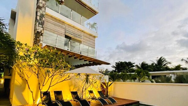 A modern building with a rooftop pool, lounge chairs, and a staircase leading to an upper level. - Beautiful Luxury 2-bed Apartment in Pereybere (Grand-Baie)