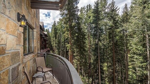 Un bâtiment en pierre doté d’un balcon donnant sur une forêt.