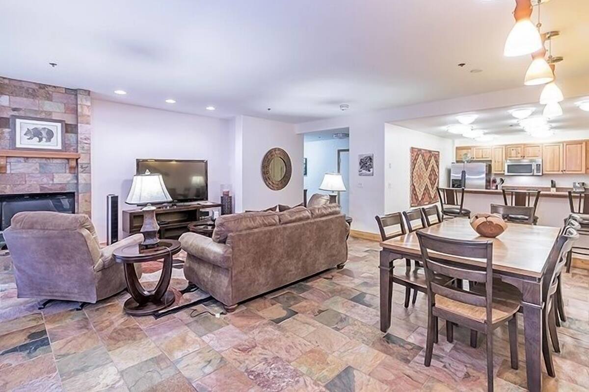 A living room with a fireplace, sofa, TV, and dining area with chairs and a table.