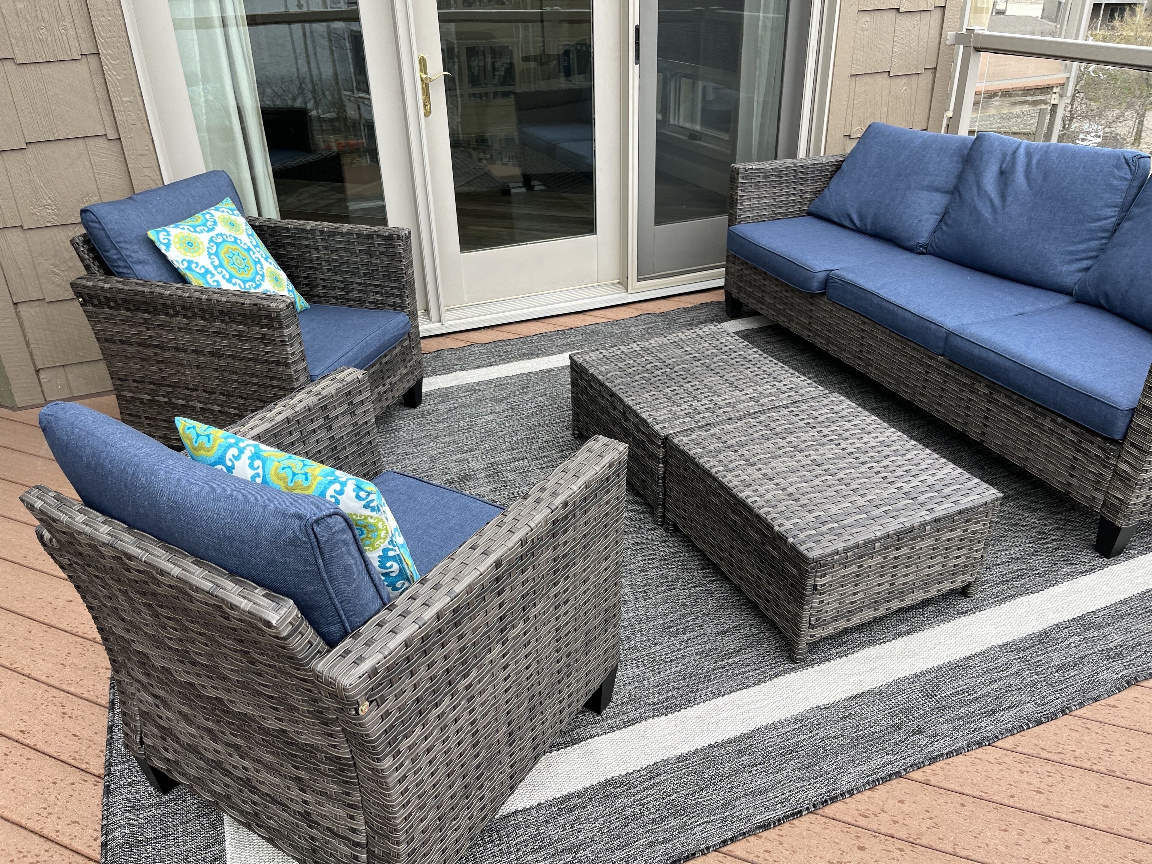 A patio area with wicker furniture, including two chairs and a sofa, and a matching ottoman.