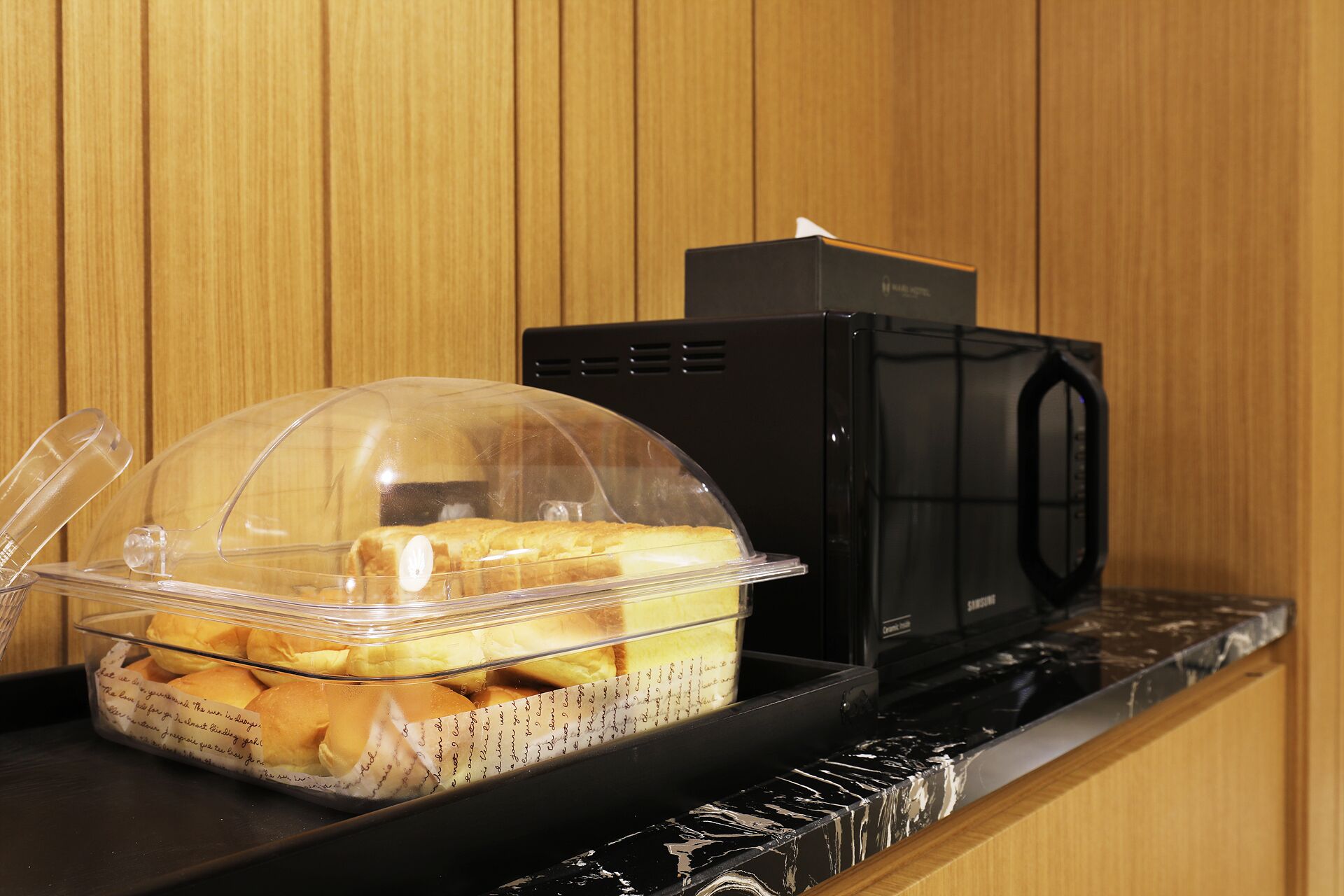A clear plastic container with a lid on a counter, next to a black microwave.
