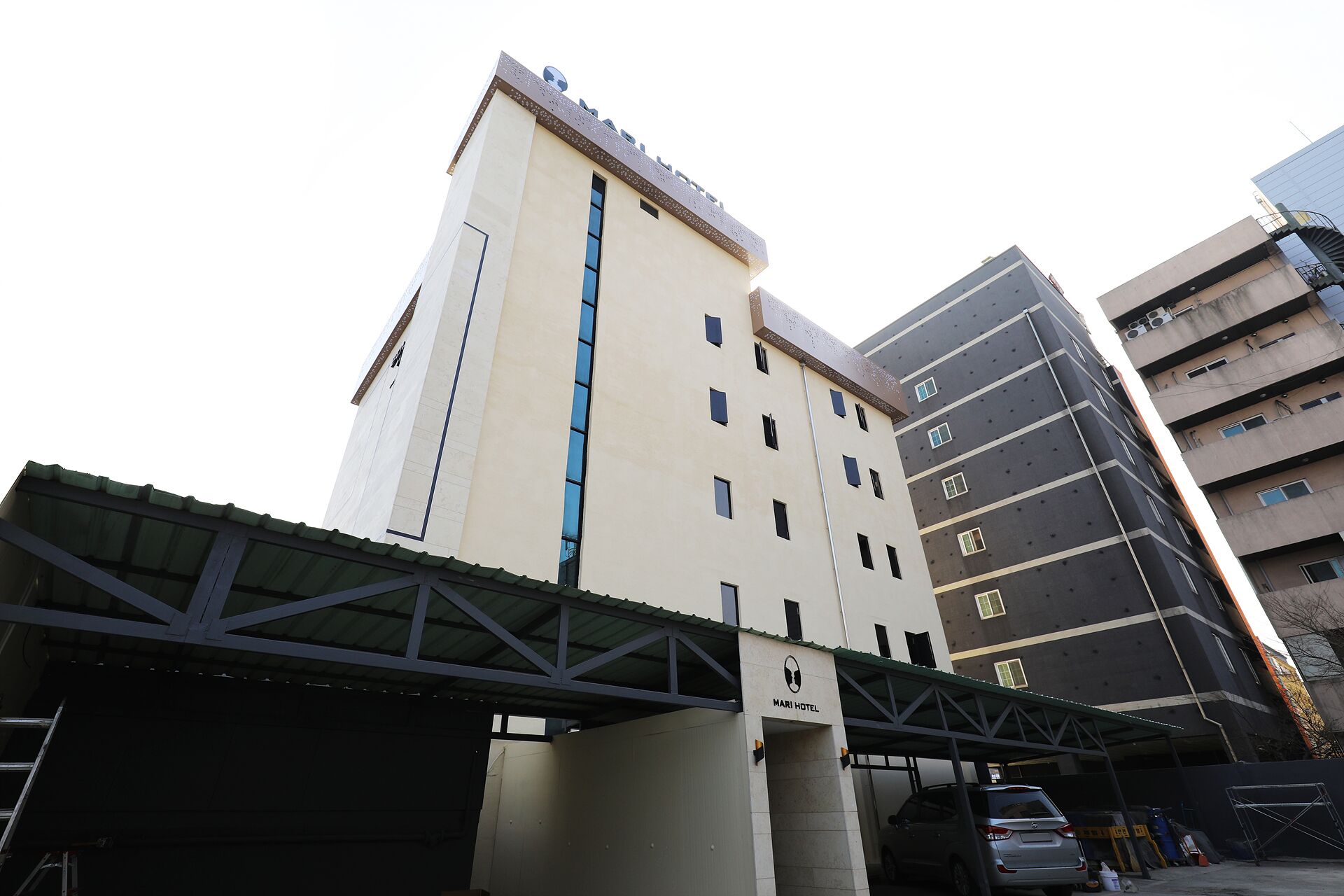 Un hotel de varios pisos con fachada plana, entrada cubierta y zona de estacionamiento.