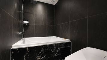 A modern bathroom with a freestanding bathtub, a toilet, and a showerhead.