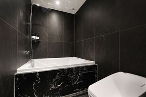 A modern bathroom with a freestanding bathtub, a toilet, and a showerhead. - Mari Hotel Chungju (Chungju)