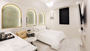 A hotel room with a bed, a small table, a sofa, and a TV mounted on the wall. - Mari Hotel Chungju (Chungju)