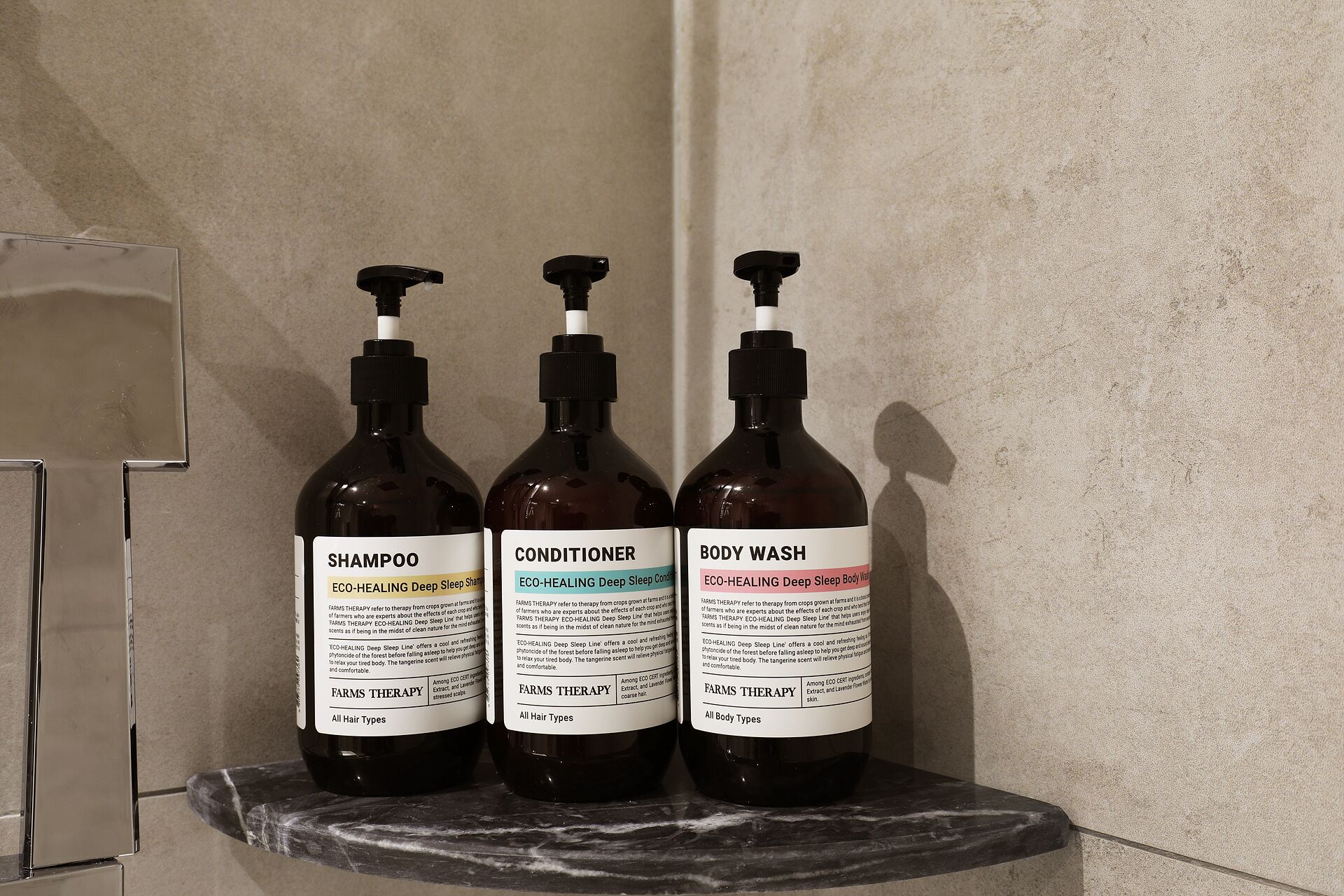 Three bottles of Farms Therapy products on a marble shelf.