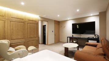 Una sala de estar moderna con un sofá, una mesa de comedor y un televisor. Hay un aparador de madera y una puerta que da a otra habitación.