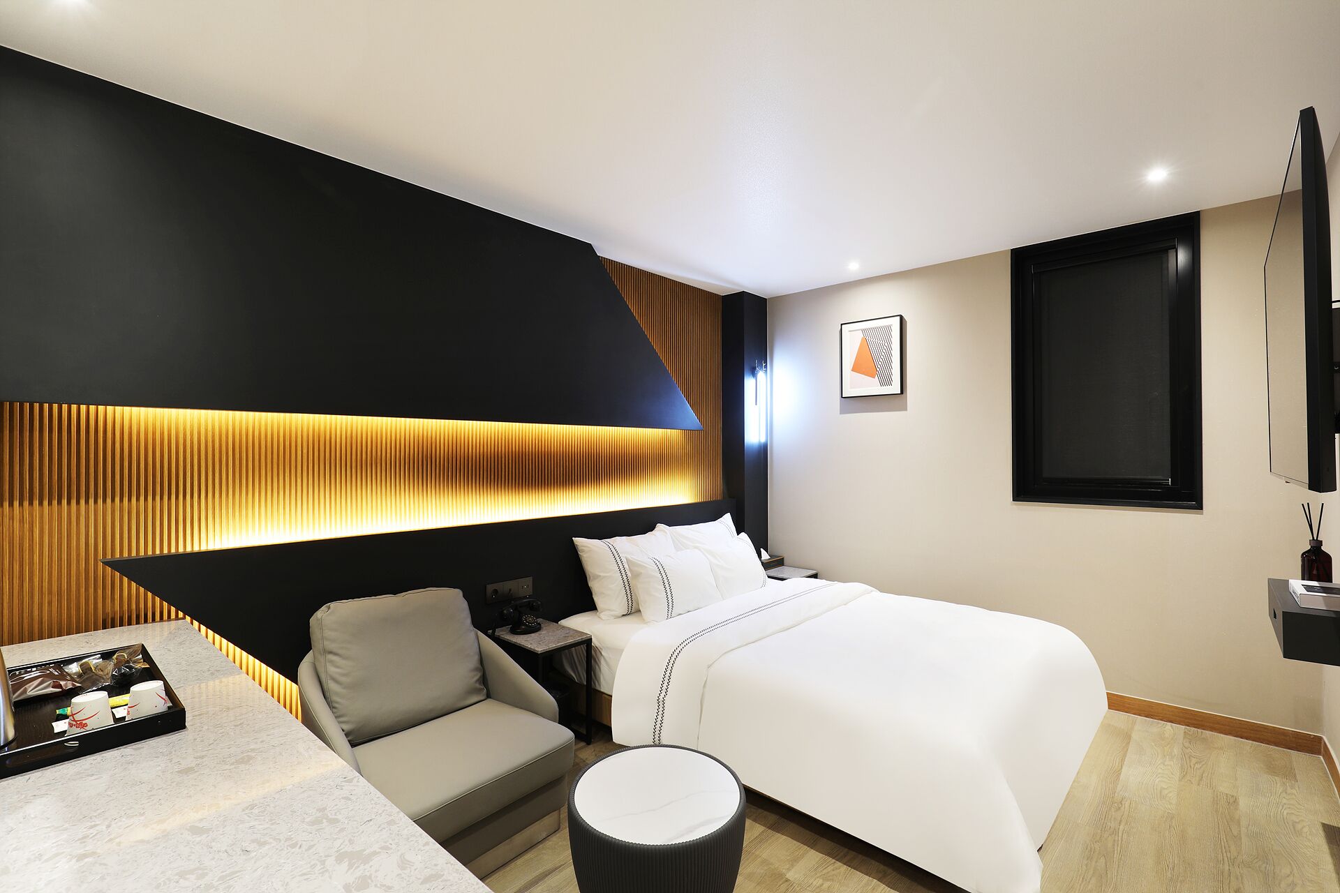 Una habitación de hotel moderna con una cama, un área de descanso y una lámpara de pared.