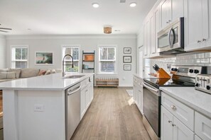 A modern kitchen with white cabinetry, a central island, and a built-in oven.