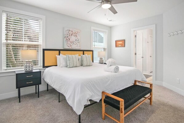 A bedroom with a bed, bedside tables, a bench, and a ceiling fan.