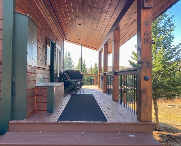 Eine Holzveranda mit Grill, Bank und Tür.