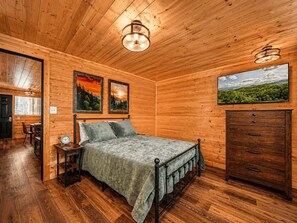 Ein Schlafzimmer mit Holzwandverkleidung, einem Bett, einem Schminktisch und zwei Wandleuchten.