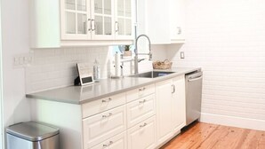 Une cuisine moderne avec des meubles blancs, une poubelle en acier inoxydable et un lave-vaisselle.
