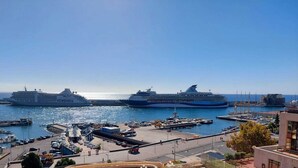 A harbor with two large cruise ships docked, a marina with boats, and a cityscape with buildings and a bridge. - Apartamento Vista Pontinha (Funchal)