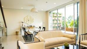 A modern living room with a sofa, dining table, chairs, and a chandelier.