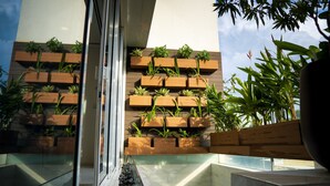 A modern building with a series of wooden planters on the exterior wall, a glass door, and a view of a pool area.