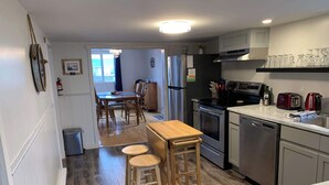 Una cocina moderna con electrodomésticos de acero inoxidable, una mesa de comedor de madera y un taburete de bar.