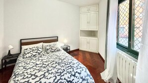 Un dormitorio con cama, mesita de noche, armario y ventana con vistas.