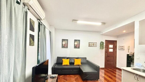 Un espacio moderno de sala con sofá, televisión y piso con patrón de espiga.
