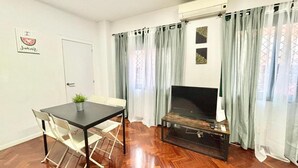 Una sala de estar con televisor, una mesa, sillas y una puerta.