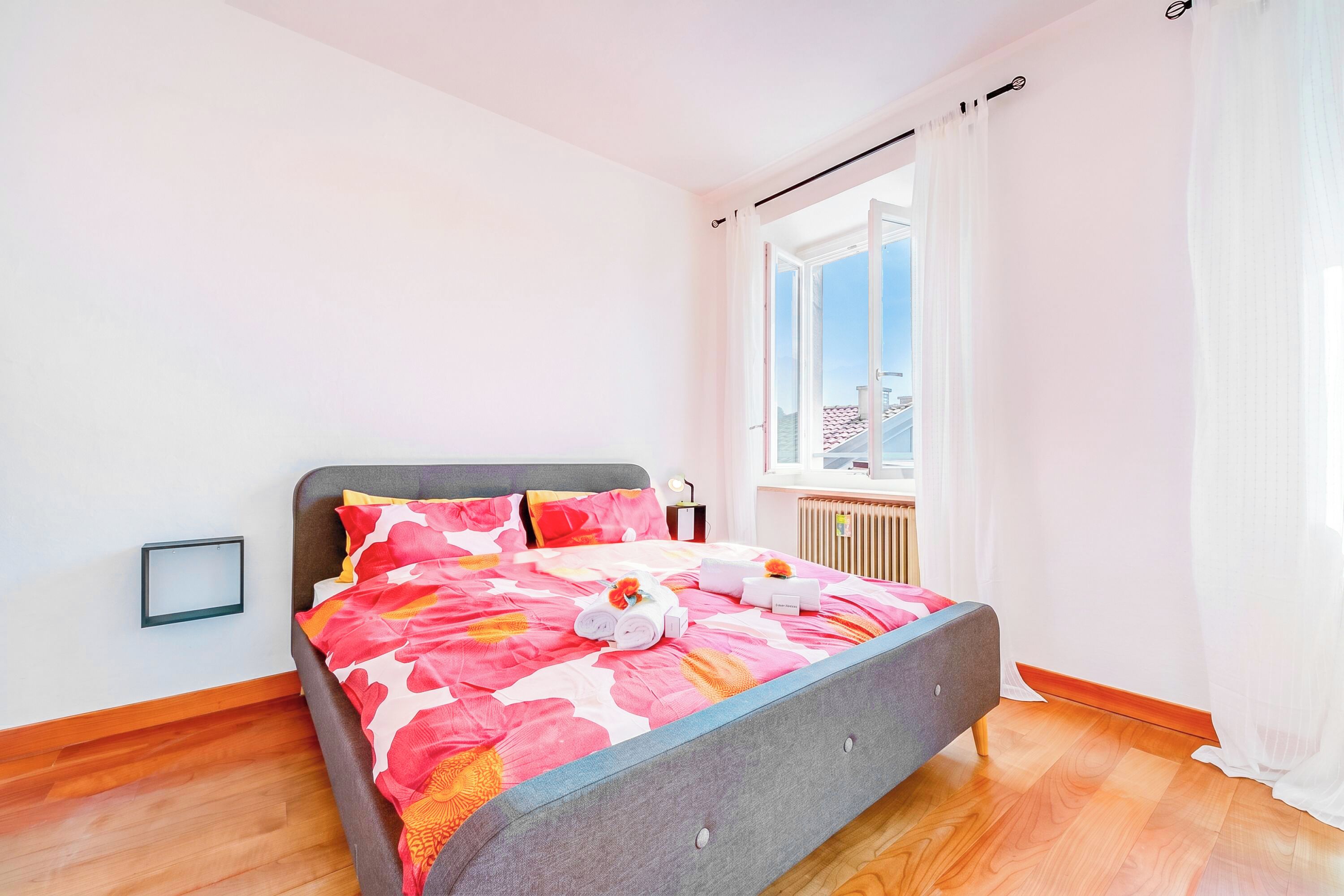 A bedroom with a bed, a window, and a radiator.