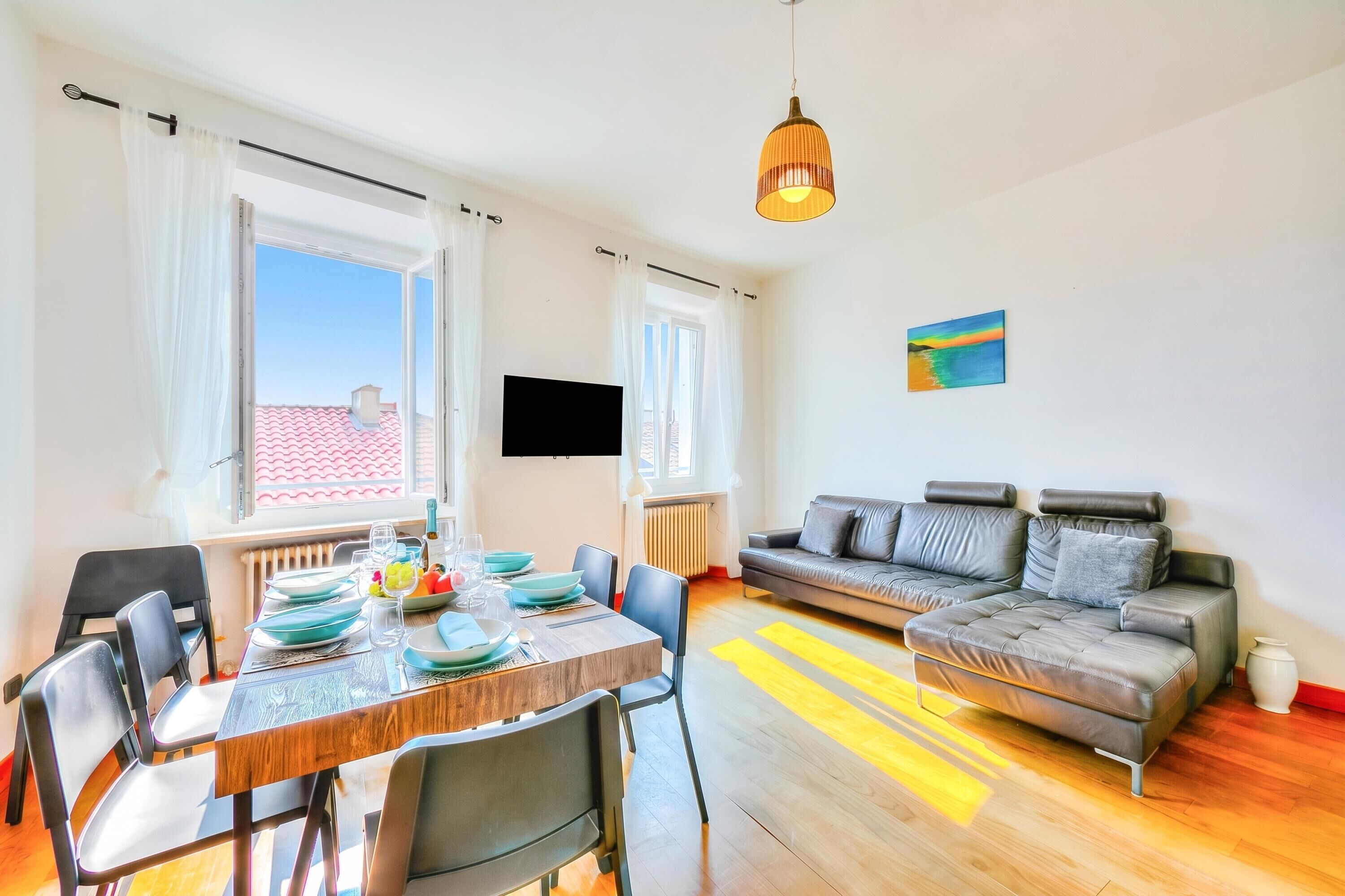 Un salon moderne comprenant un canapé, une table à manger, des chaises et un téléviseur.