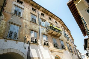 A historic building with multiple windows, some with shutters, and a balcony with plants. - Muri Di Arco (Arco)