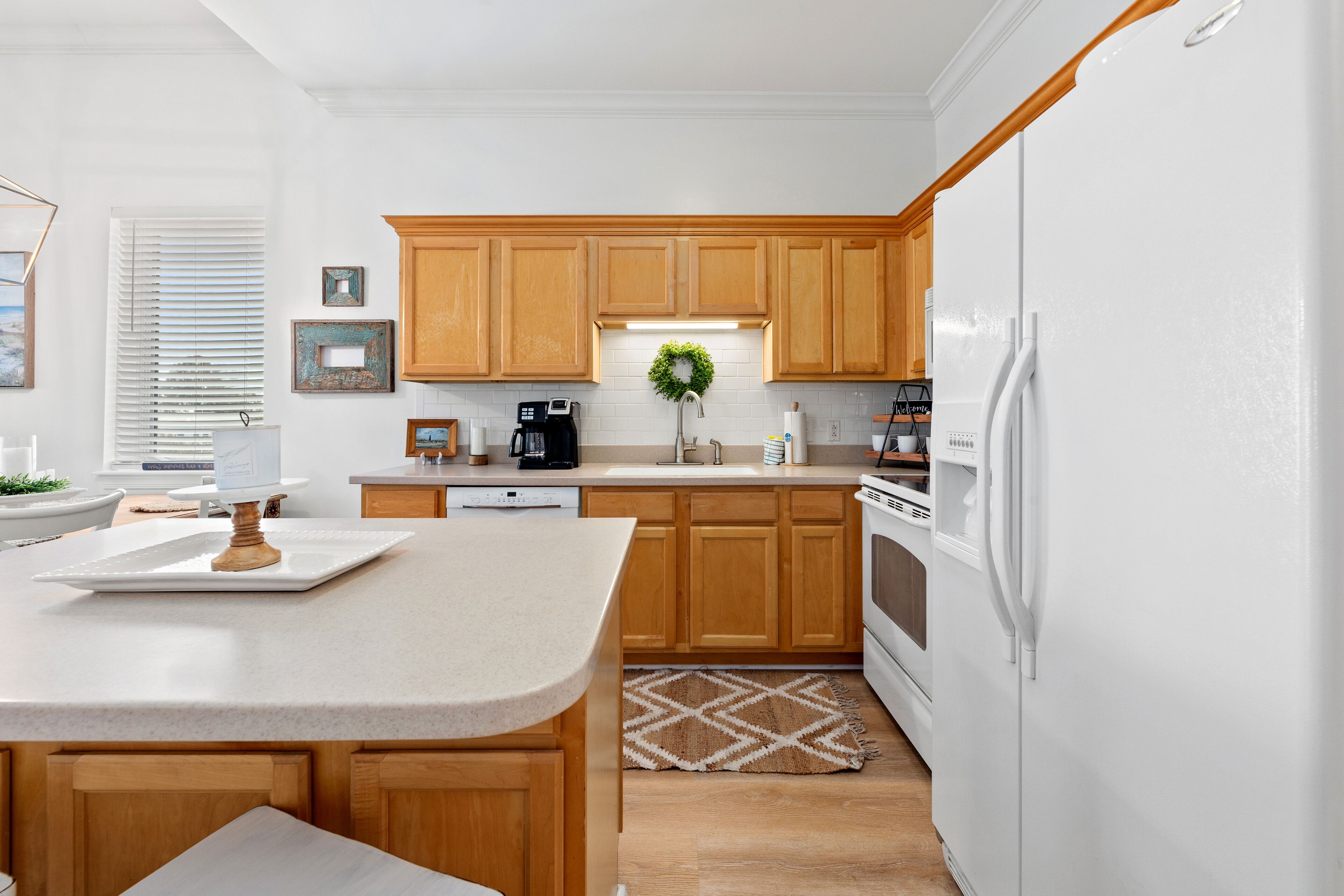 A modern kitchen with wooden cabinets, a white refrigerator, and a central island.