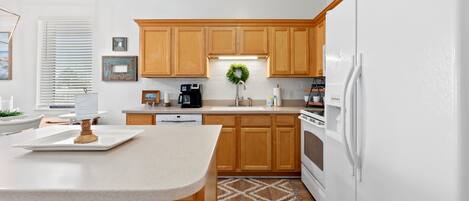 A modern kitchen with wooden cabinets, a white refrigerator, and a central island.