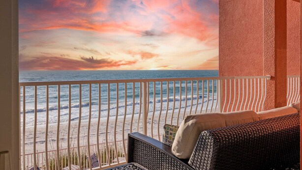A balcony with a view of the ocean and a sunset.