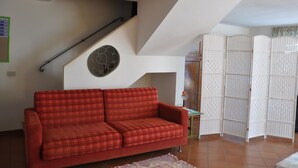En stue med en rød ternet sofa, en trappe og en hvid rumdeler.